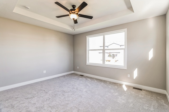 carpeted empty room featuring a tray ceiling and ceiling fan