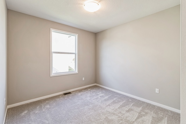 carpeted empty room with a textured ceiling