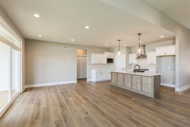 kitchen featuring wall chimney exhaust hood, white cabinetry, and a healthy amount of sunlight