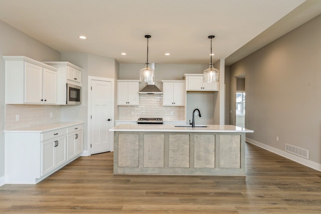 kitchen featuring white cabinetry, light hardwood / wood-style floors, sink, and a center island with sink