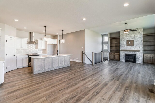 406 NE 57th Ct, Ankeny, IA 50021 - kitchen with wall chimney range hood, a ceiling fan, gas stove, and wood finished floors