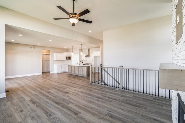 unfurnished living room with dark wood-type flooring, ceiling fan, sink, and a fireplace