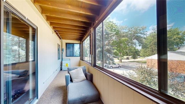 sunroom / solarium featuring beamed ceiling and a healthy amount of sunlight