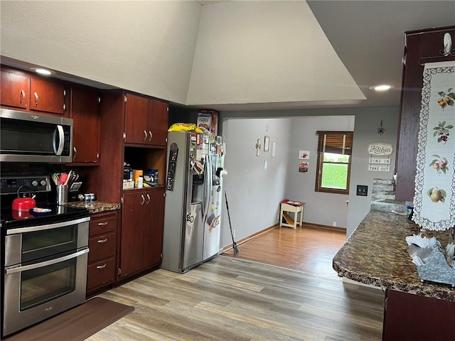 kitchen with stainless steel appliances, light hardwood / wood-style floors, and dark stone counters