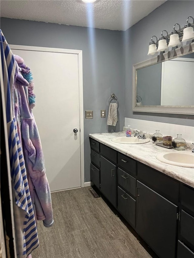 507 E Main St, Le Grand, IA 50142 - bathroom with wood finished floors, double vanity, and a textured ceiling