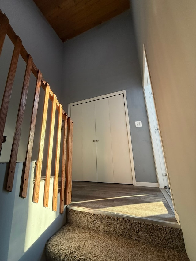 stairway featuring a towering ceiling and wooden ceiling