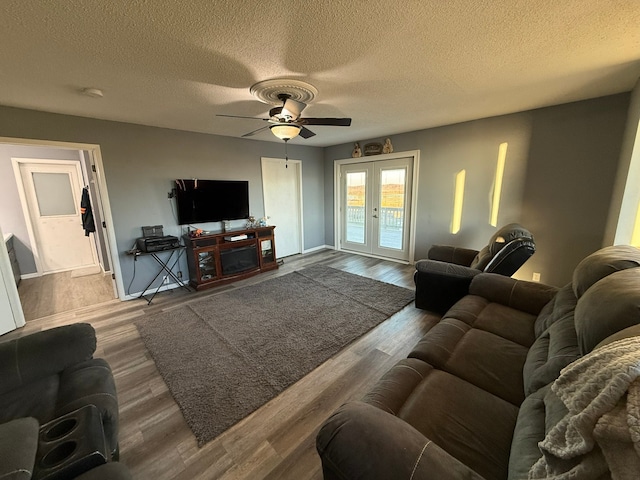 living room with ceiling fan, french doors, wood-type flooring, and a textured ceiling