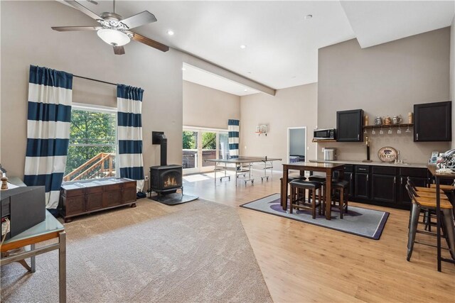 living room featuring a wood stove, light wood-type flooring, a wealth of natural light, and ceiling fan