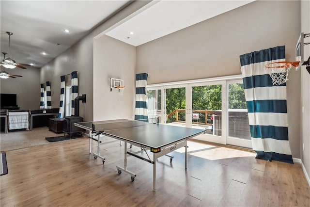 rec room with ceiling fan, wood-type flooring, and a towering ceiling