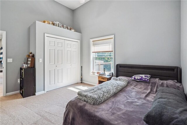 bedroom featuring a towering ceiling, light colored carpet, and a closet