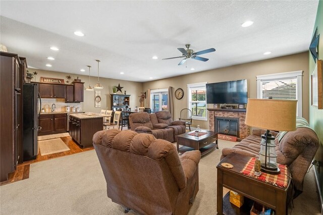 living room with a fireplace, light hardwood / wood-style floors, and ceiling fan