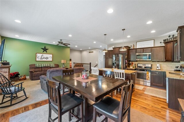 dining space with sink, ceiling fan, and light wood-type flooring