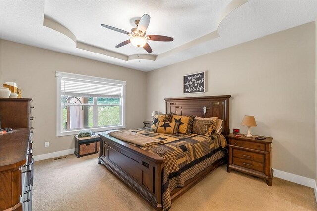 carpeted bedroom featuring ceiling fan, a textured ceiling, and a tray ceiling