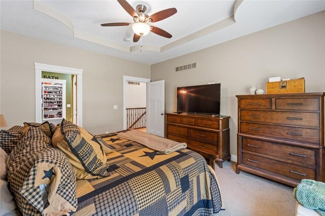 carpeted bedroom with ceiling fan and a tray ceiling