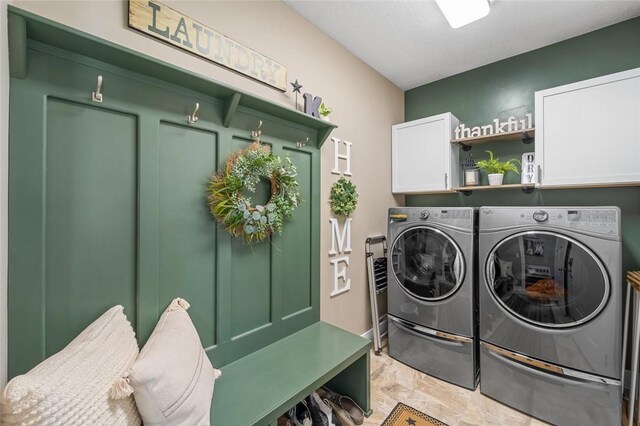 washroom featuring washing machine and clothes dryer, cabinets, and light tile patterned flooring