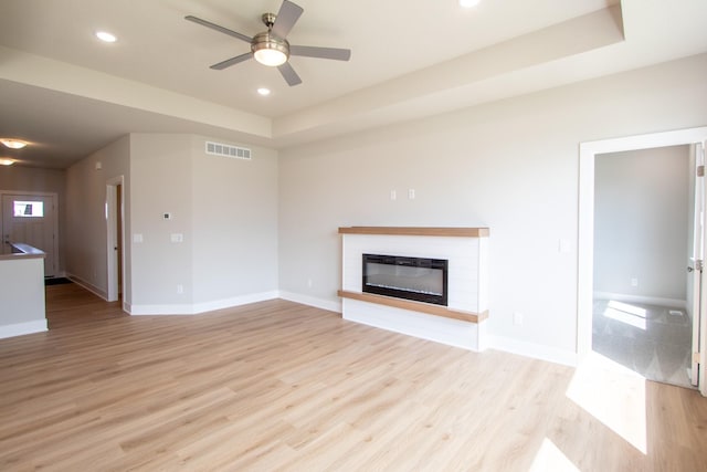 1303 NW Benjamin Dr, Ankeny, IA 50023 - unfurnished living room featuring light wood-style flooring, baseboards, a glass covered fireplace, visible vents, and ceiling fan