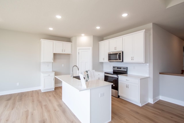 1303 NW Benjamin Dr, Ankeny, IA 50023 - kitchen with a kitchen island with sink, a sink, light wood-style floors, and appliances with stainless steel finishes