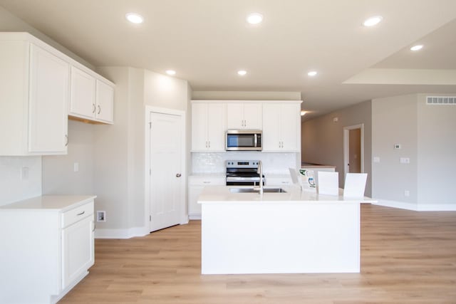 1303 NW Benjamin Dr, Ankeny, IA 50023 - kitchen with light wood finished floors, stainless steel appliances, backsplash, visible vents, and baseboards