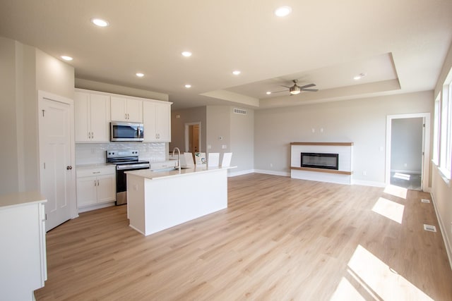 1303 NW Benjamin Dr, Ankeny, IA 50023 - kitchen featuring ceiling fan, baseboards, a raised ceiling, and appliances with stainless steel finishes