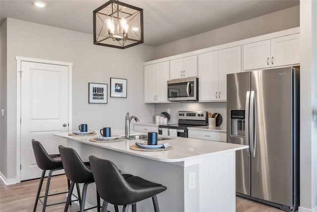 kitchen with a kitchen island with sink, hanging light fixtures, white cabinetry, and appliances with stainless steel finishes