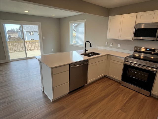 kitchen featuring white cabinets, kitchen peninsula, sink, and appliances with stainless steel finishes