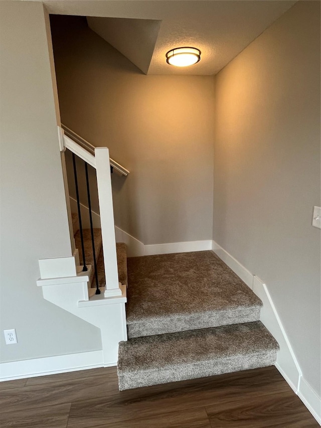 staircase featuring a textured ceiling and hardwood / wood-style flooring