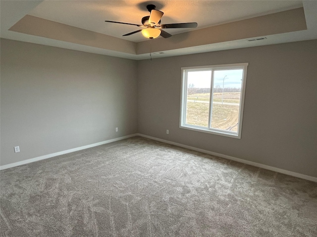 spare room with carpet flooring, a tray ceiling, and ceiling fan