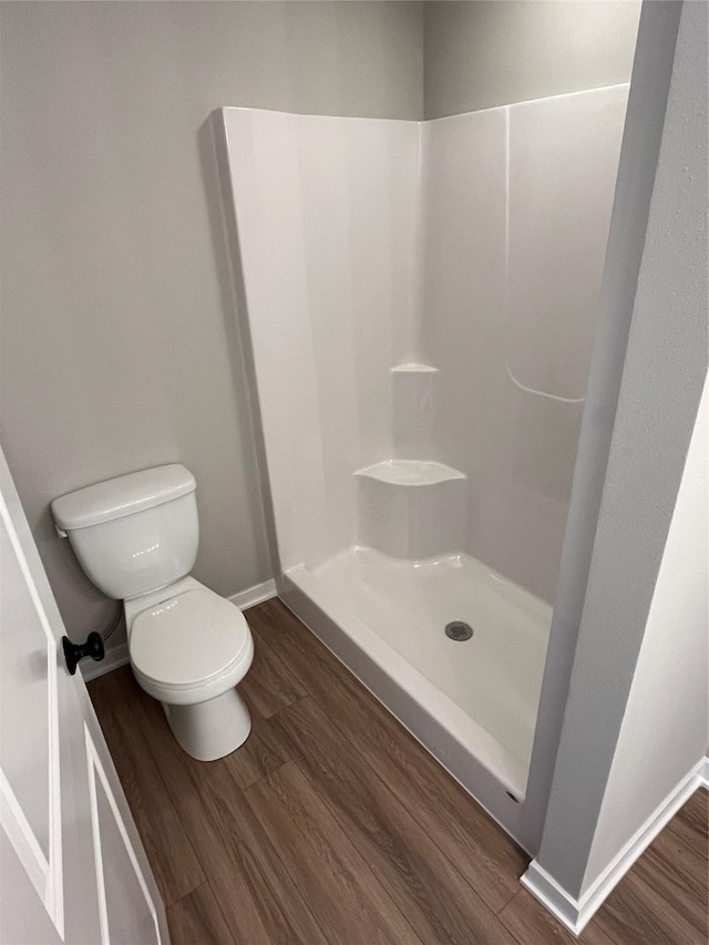 bathroom featuring a shower, hardwood / wood-style floors, and toilet