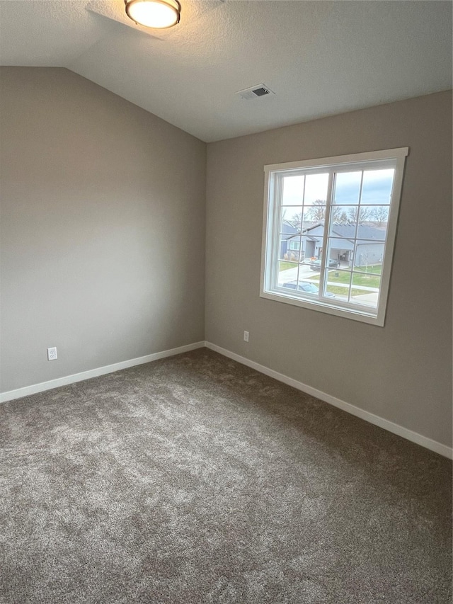 unfurnished room featuring carpet, a textured ceiling, and vaulted ceiling