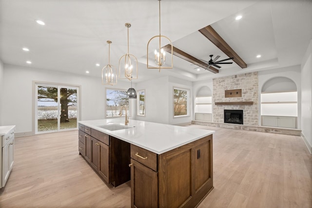 kitchen with a kitchen island with sink, sink, decorative light fixtures, and light hardwood / wood-style flooring