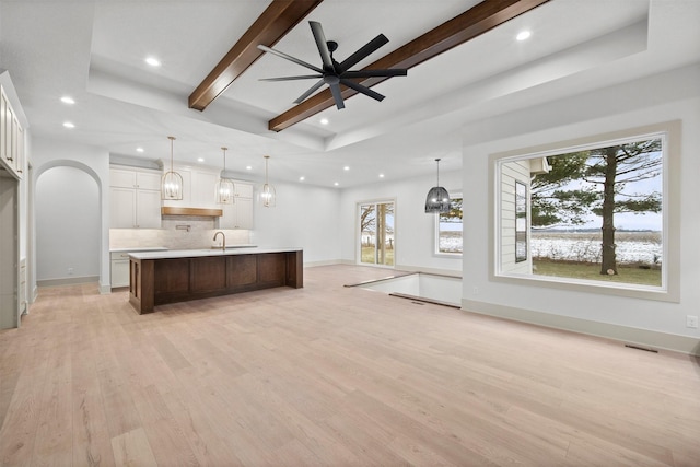 kitchen featuring white cabinetry, pendant lighting, a large island with sink, and light hardwood / wood-style floors