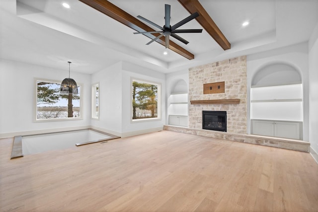 unfurnished living room featuring ceiling fan, built in shelves, light wood-type flooring, and a fireplace