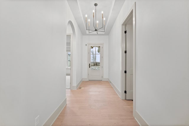 corridor featuring light wood-type flooring and a chandelier