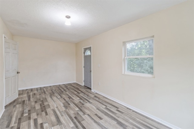 unfurnished room with wood-type flooring and a textured ceiling