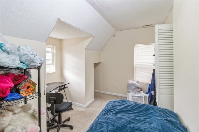 bedroom with a textured ceiling, light carpet, and vaulted ceiling