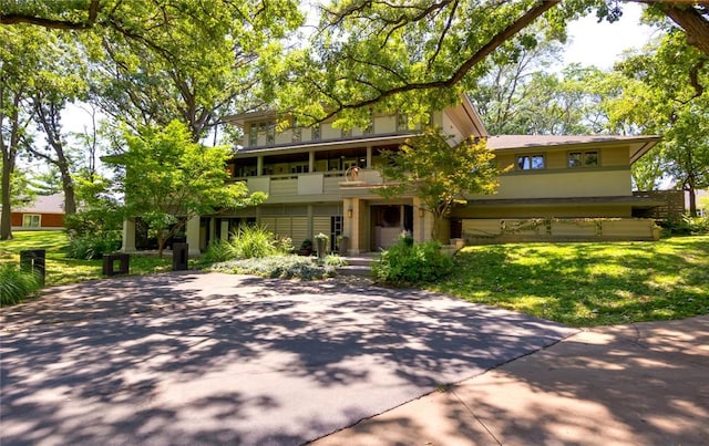 view of front of home featuring a front lawn, a balcony, and stucco siding