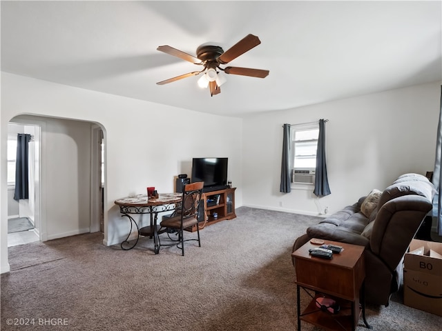 living area featuring carpet floors, arched walkways, ceiling fan, and baseboards