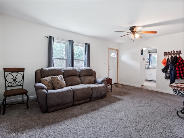 carpeted living room with arched walkways, ceiling fan, and baseboards