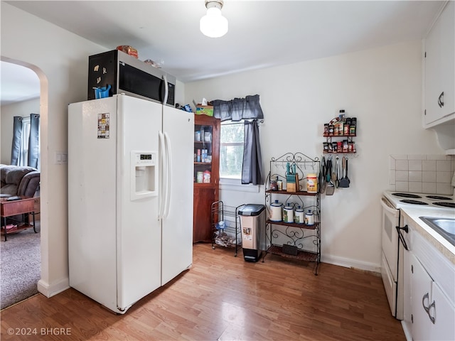 kitchen with white appliances, tasteful backsplash, arched walkways, light wood-type flooring, and white cabinetry