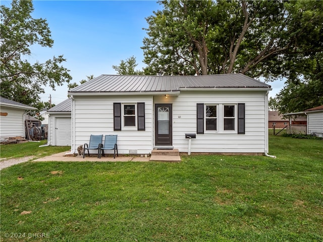 view of front of home featuring a garage, entry steps, metal roof, and a front yard