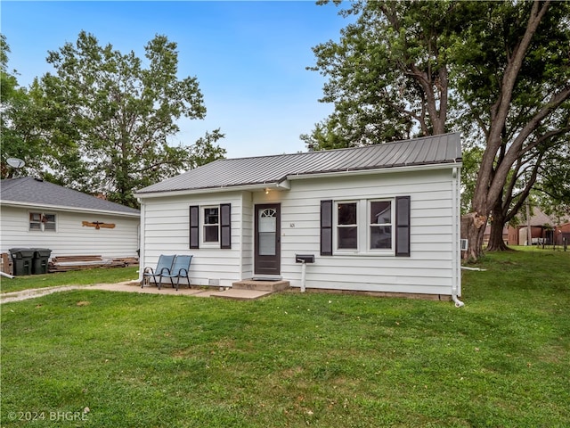 view of front of property featuring metal roof, a patio, and a front yard