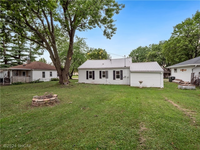 back of house featuring an outdoor fire pit, metal roof, and a lawn