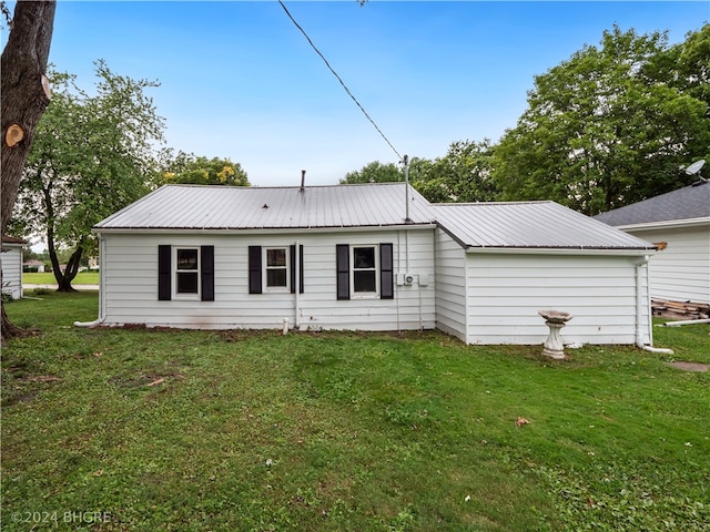 rear view of house with metal roof and a yard