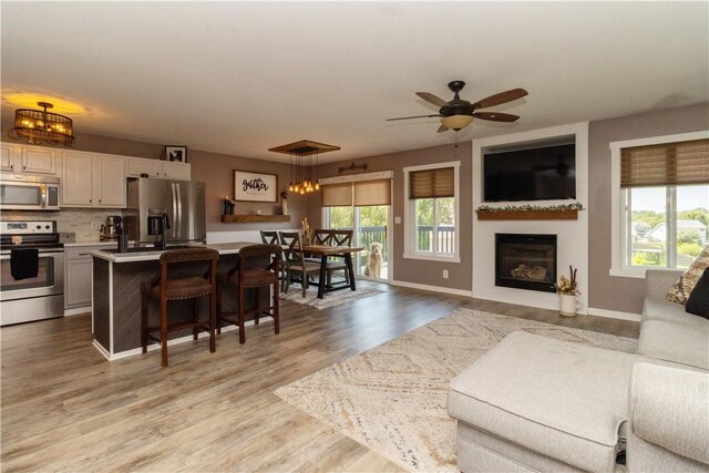 living room featuring light hardwood / wood-style flooring and ceiling fan with notable chandelier