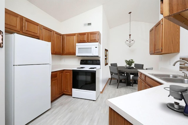 kitchen featuring white appliances, lofted ceiling, pendant lighting, sink, and light wood-type flooring