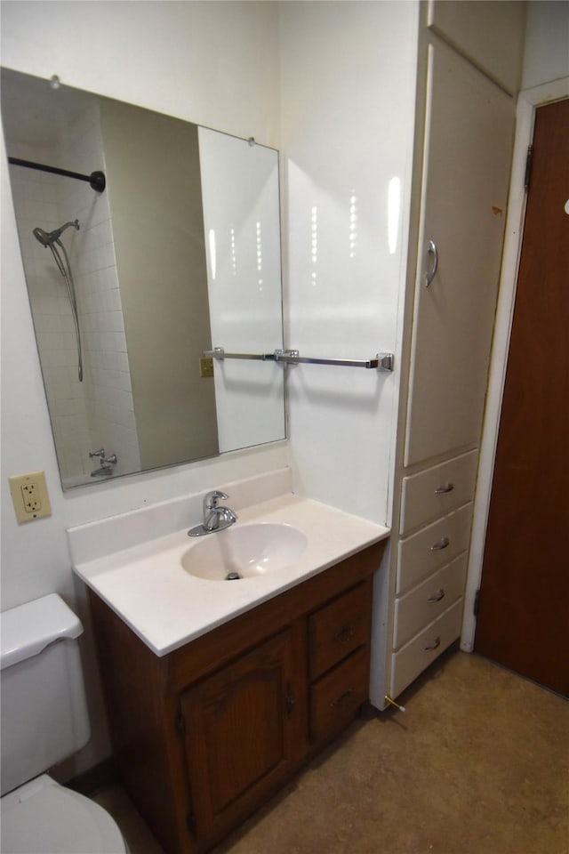 bathroom featuring vanity, a tile shower, and toilet