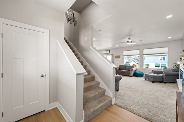 stairway with ceiling fan and light hardwood / wood-style flooring