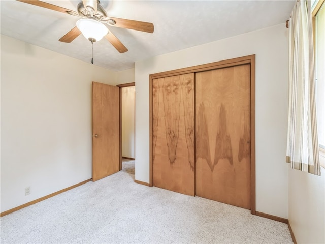 unfurnished bedroom featuring ceiling fan, light carpet, and a closet