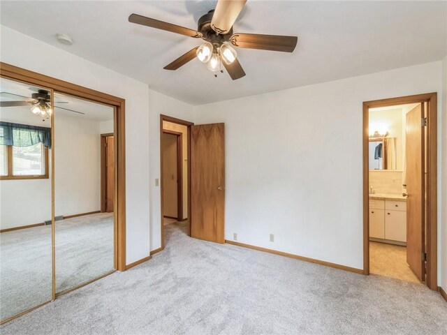 unfurnished bedroom featuring ceiling fan, a closet, light colored carpet, and ensuite bathroom