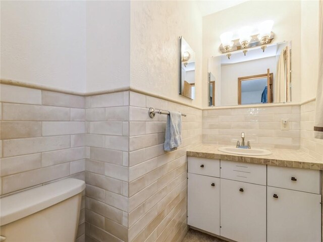 bathroom with vanity, tile walls, toilet, and decorative backsplash